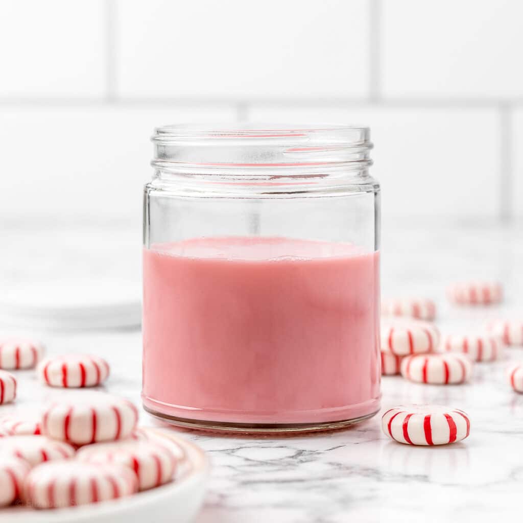 Peppermint Simple Syrup in a jar surrounded by peppermint candies and the jar's lid.