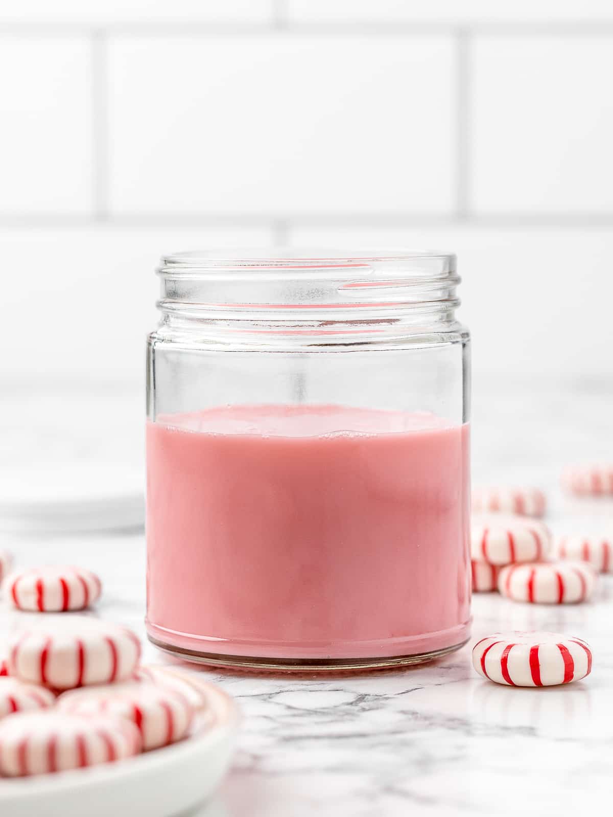 Peppermint Simple Syrup in a jar surrounded by peppermint candies.