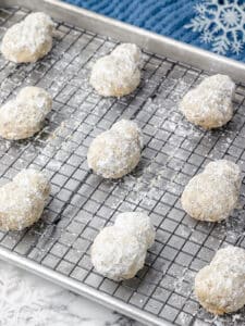 Two layer snowmen on a rack lined baking sheet baked and rolled in powdered sugar.