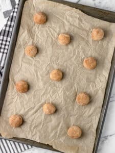 Snickerdoodles on a parchment lined baking sheet ready to go into the oven.