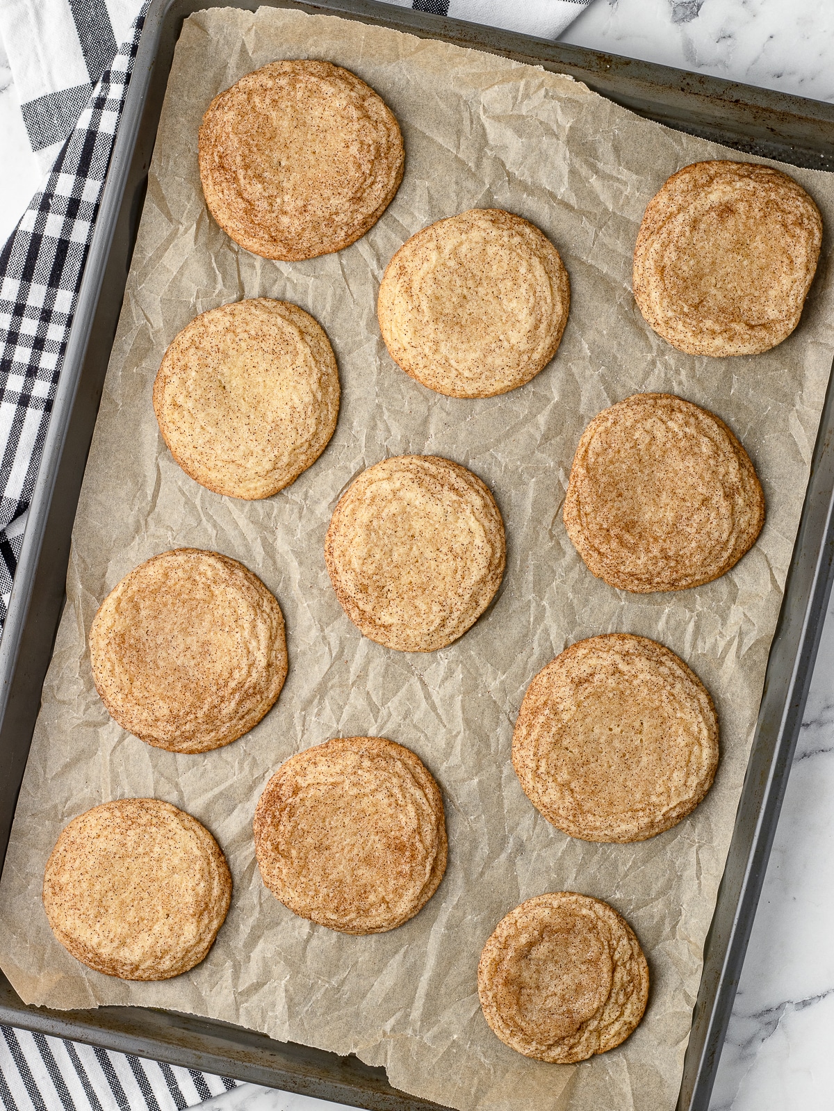 Snickerdoodles on a parchment lined baking sheet after they have been baked.