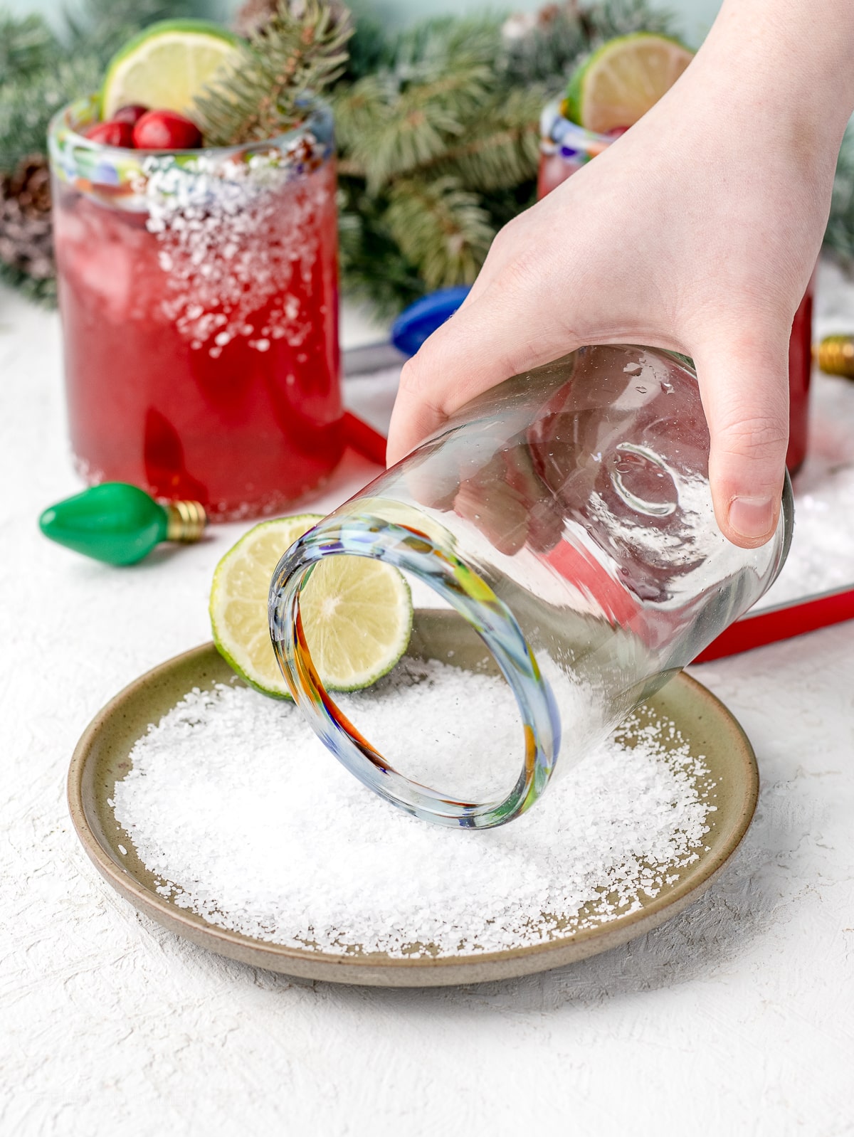 Hand holding a glass and dipping it into a shallow dish of salt.