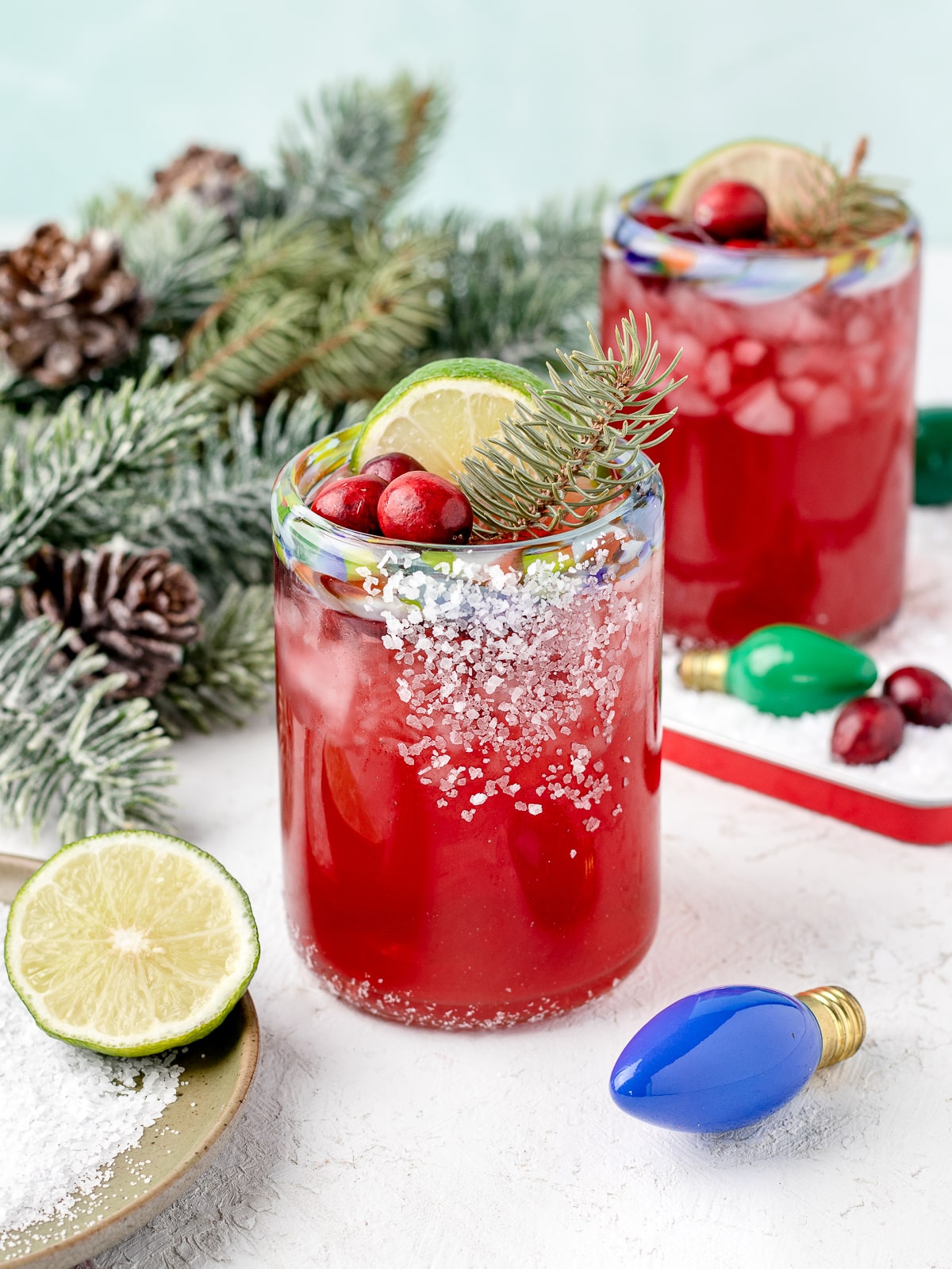 Alcohol free cranberry margarita mocktail with salted glass, lime slice, and fresh cranberry garnish.