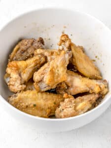 Baked wings in a bowl tossed in soy garlic sauce.