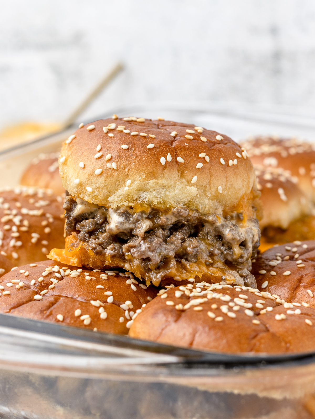 Cheesy Ground Beef Slider with gooey cheese and sriracha aioli sauce squeezing out.