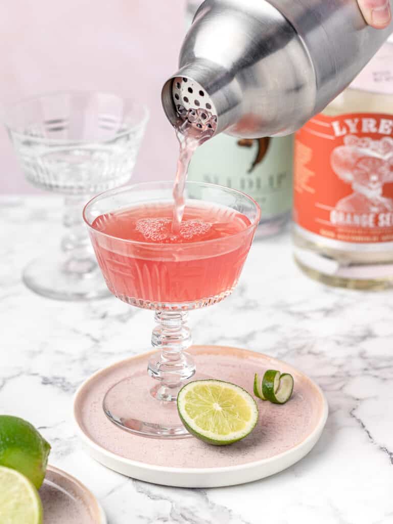 Pouring Cosmopolitan into martini coupe glass.