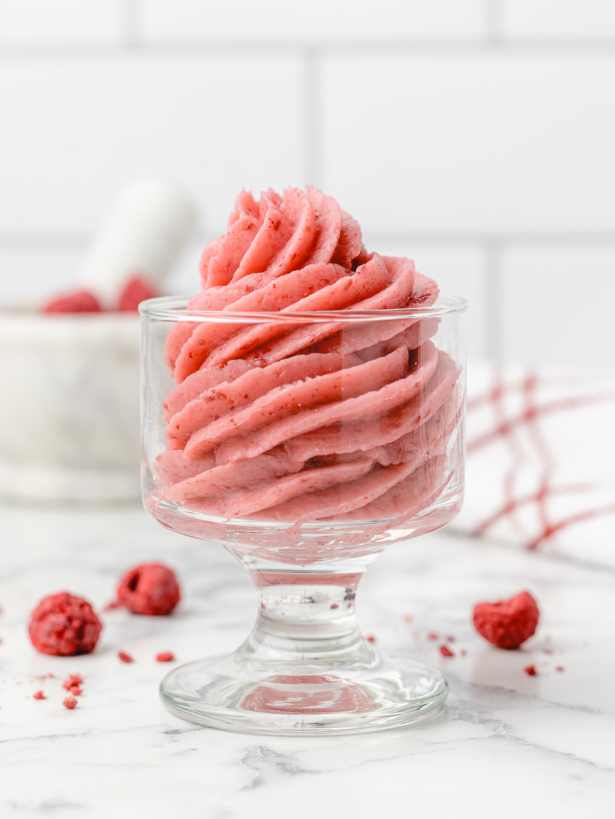 A small ice cream dish with swirls of piped pink Raspberry Buttercream Frosting.