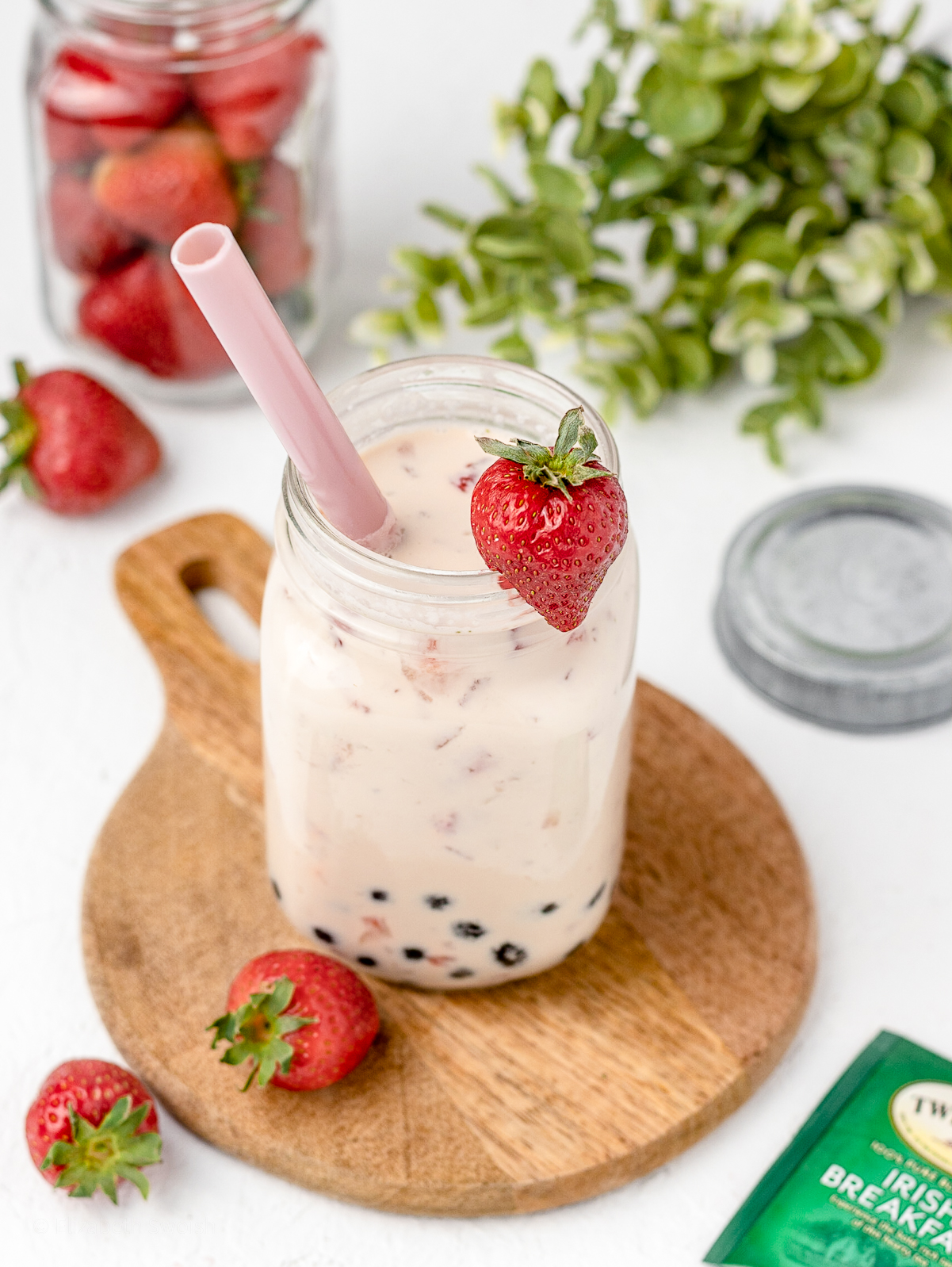 Strawberry Milk Tea with boba and fresh strawberries. Surrounded by more fresh strawberries.