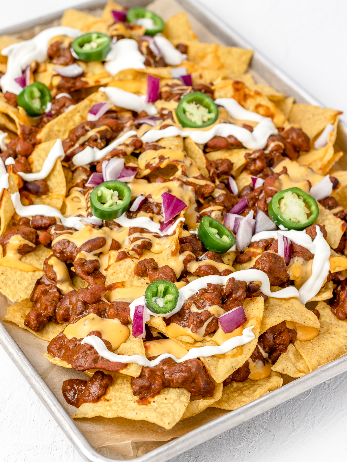 Chili Cheese Nachos Baked with sour cream, red onion, and jalapenos.