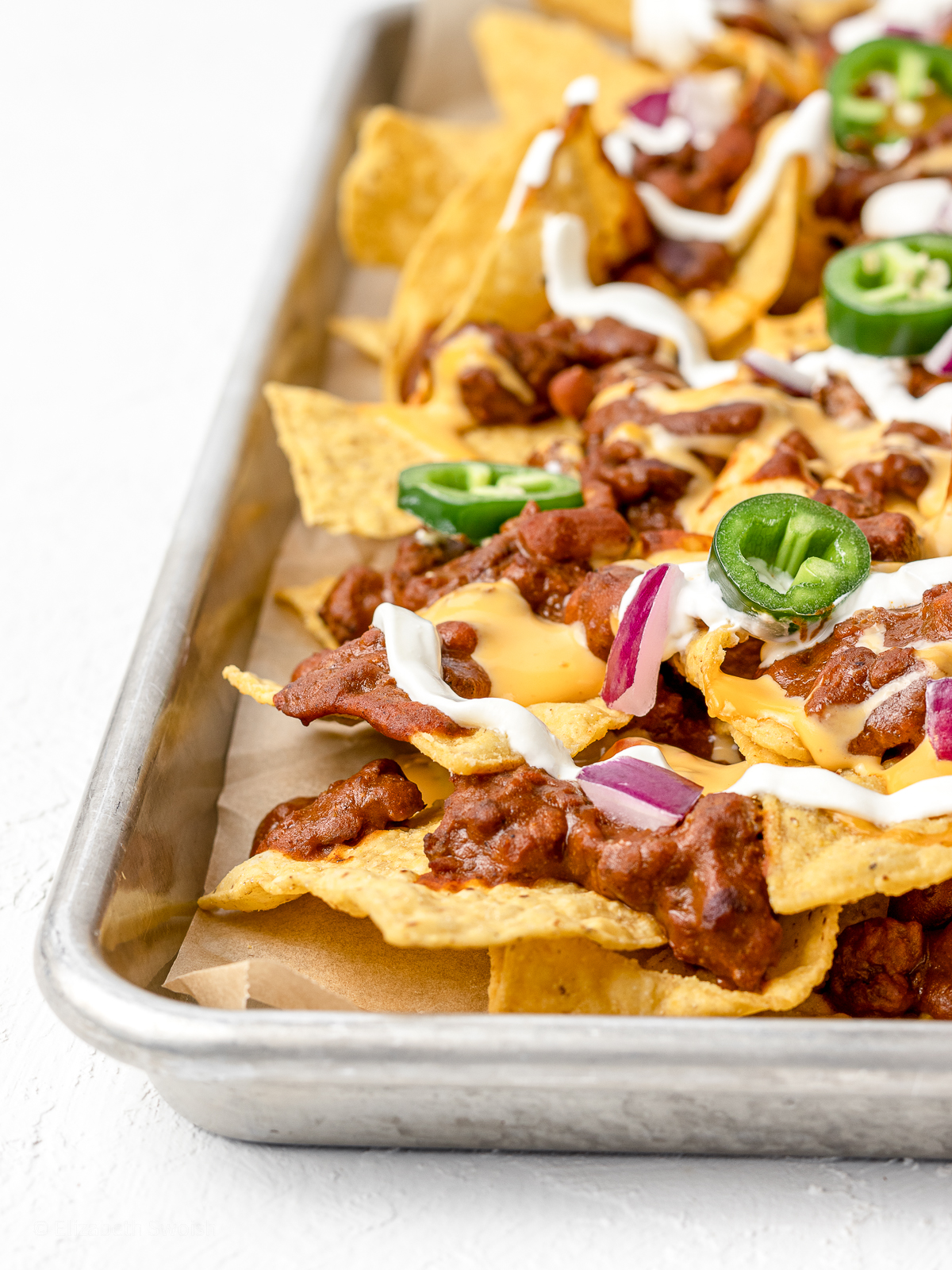 Baked loaded Chili Cheese Nachos on a large baking sheet.