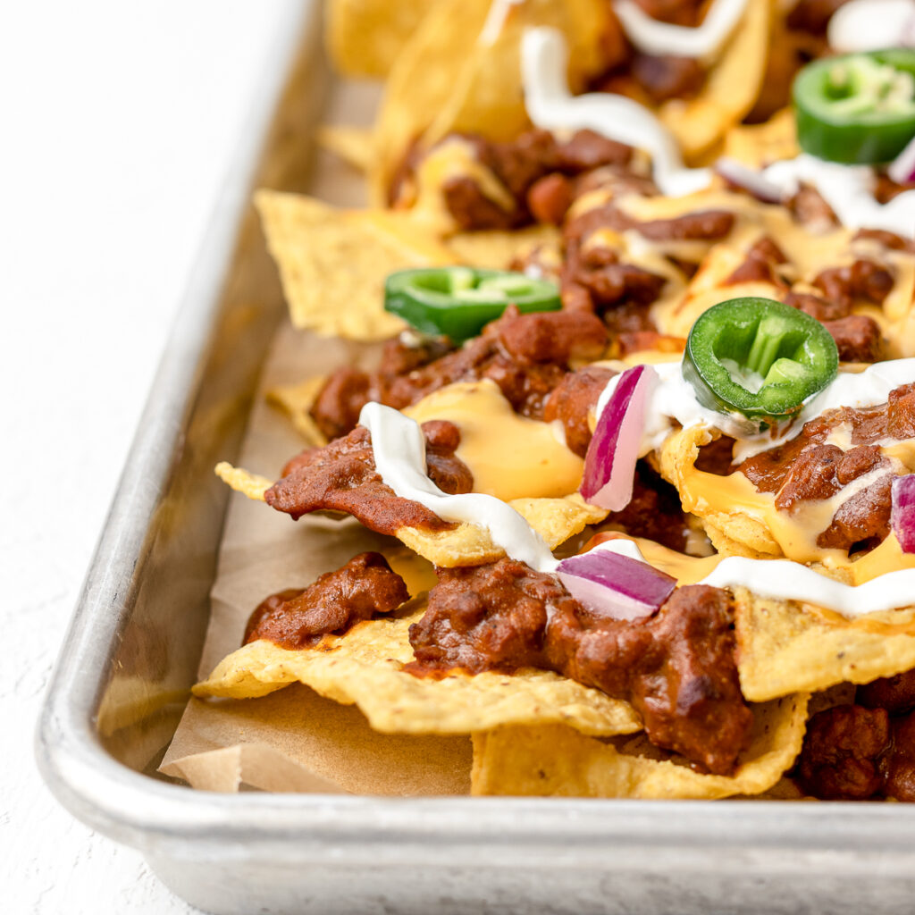 Loaded and baked Chili Cheese Nachos on a large baking sheet.