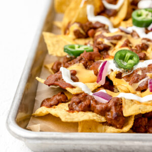 Loaded and baked Chili Cheese Nachos on a large baking sheet.