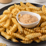 A small dish of creamy, smoky, ands spicy Chipotle Southwest Sauce surrounded by crinkle French fries.