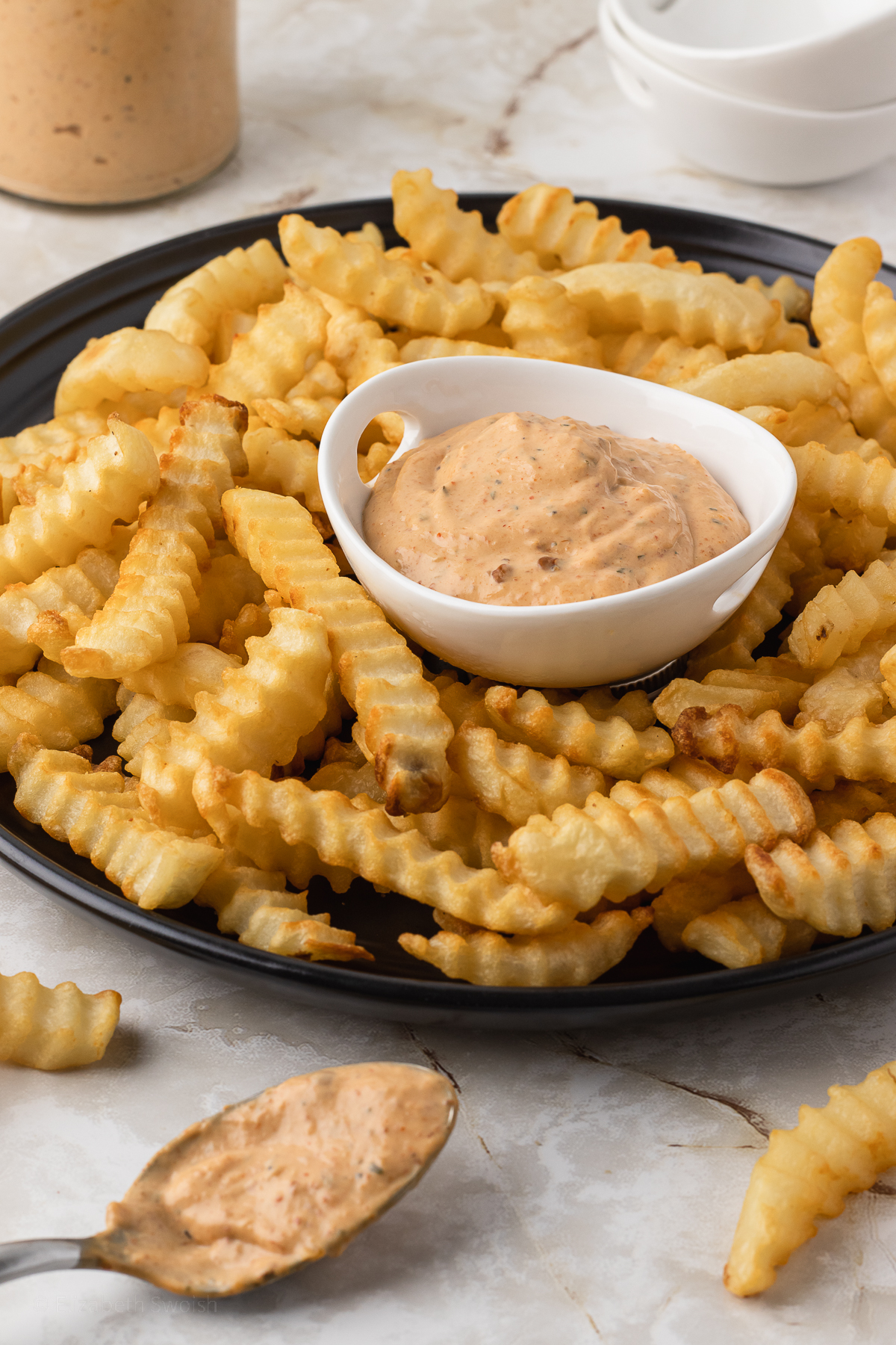 A small dish of Chipotle Southwest Sauce surrounded by crinkle French fries.