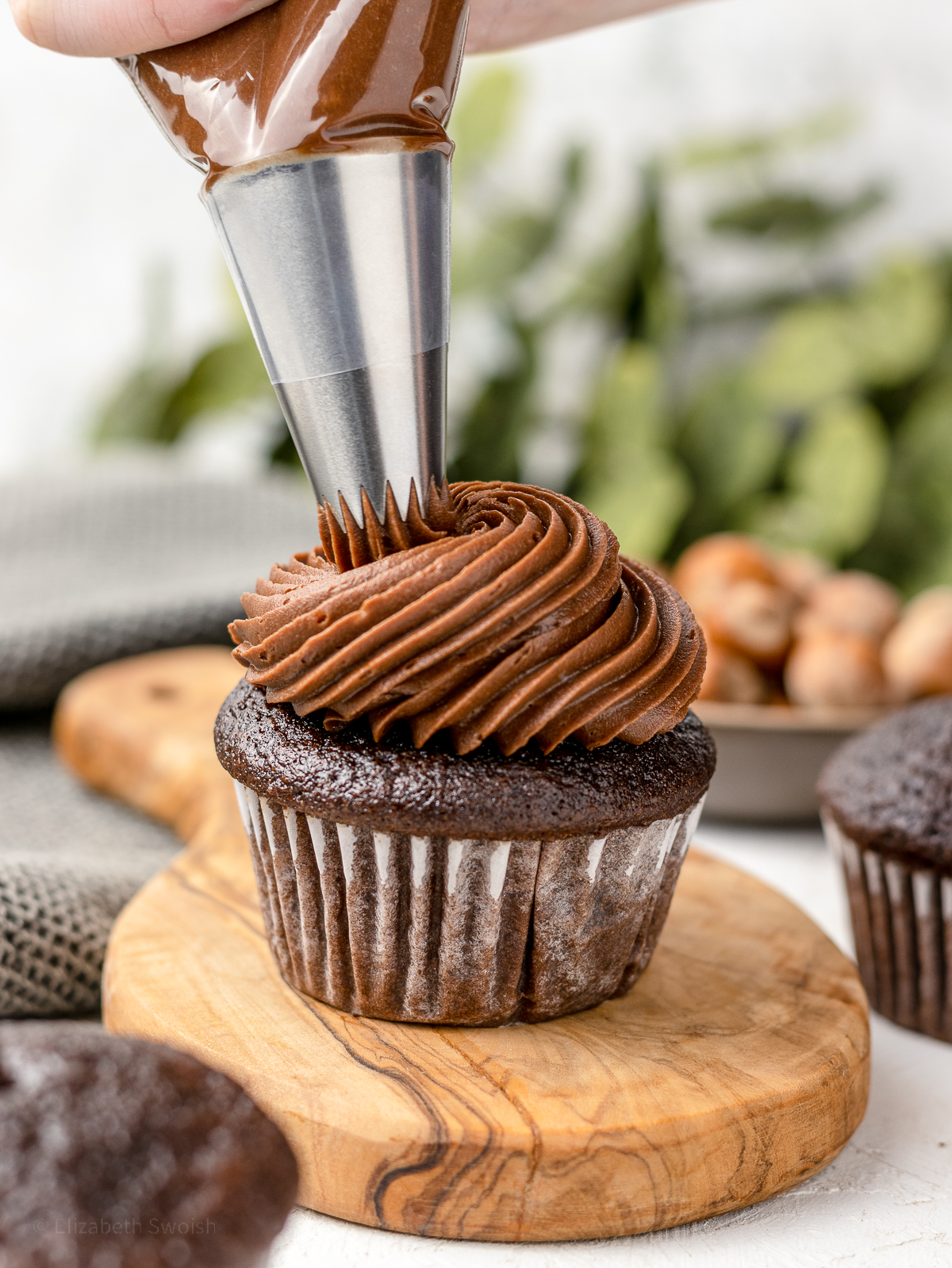 Piping chocolate Nutella buttercream onto a Nutella filled cupcake.