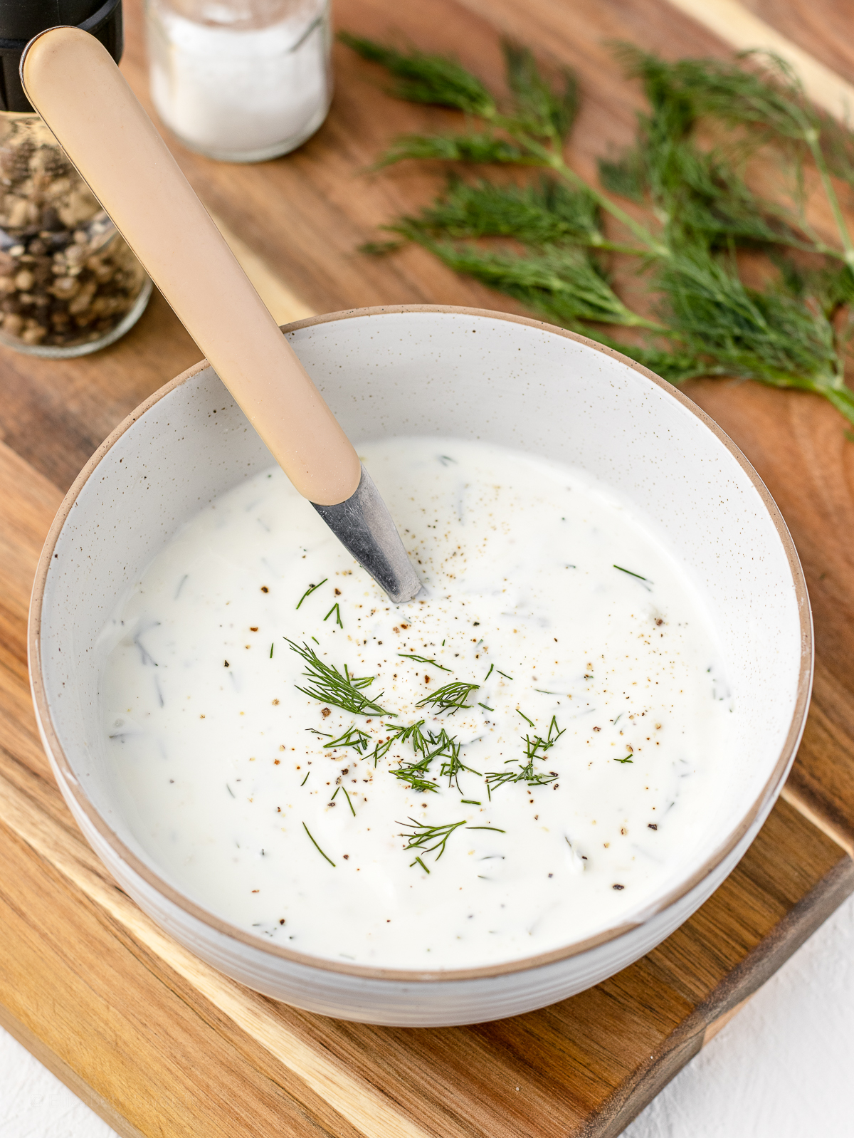 Bowl of Dill Sauce with a spoon, ready to serve out.