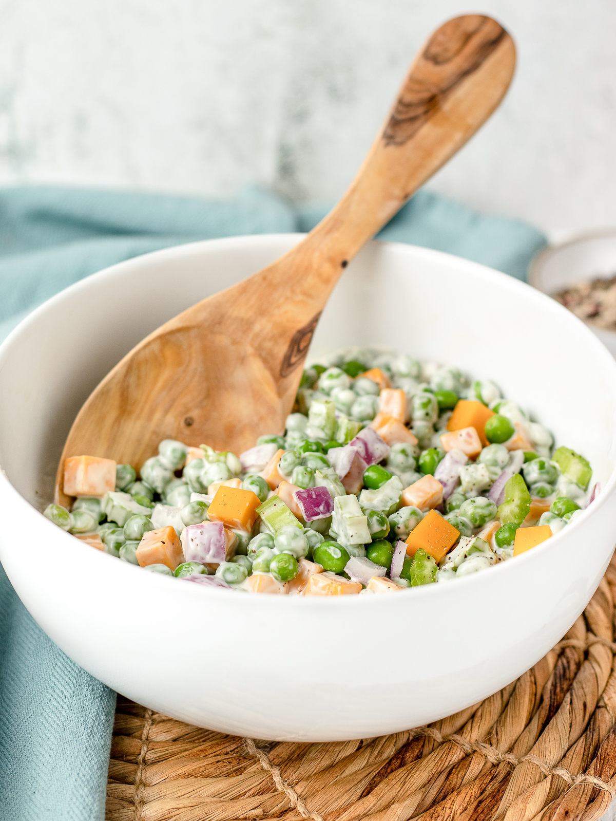 Spoon in a large bowl of colorful pea salad.