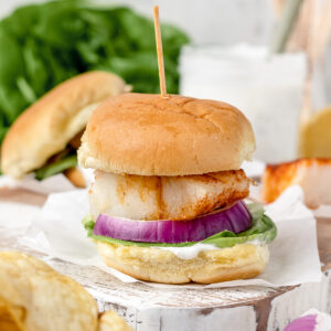Baked Cod Fish Sliders with lettuce, red onion, and yogurt dill sauce. Potato chips and more sauce served on the side.