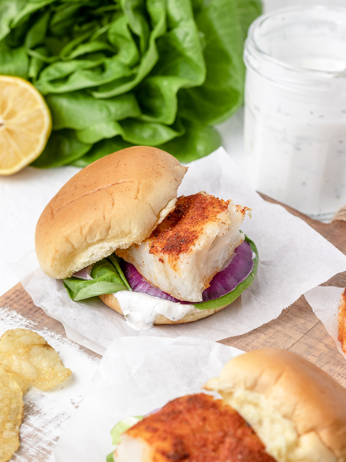 A baked cod fish sliders with top buns on the side and flaky, paprika seasoned cod fish exposed.