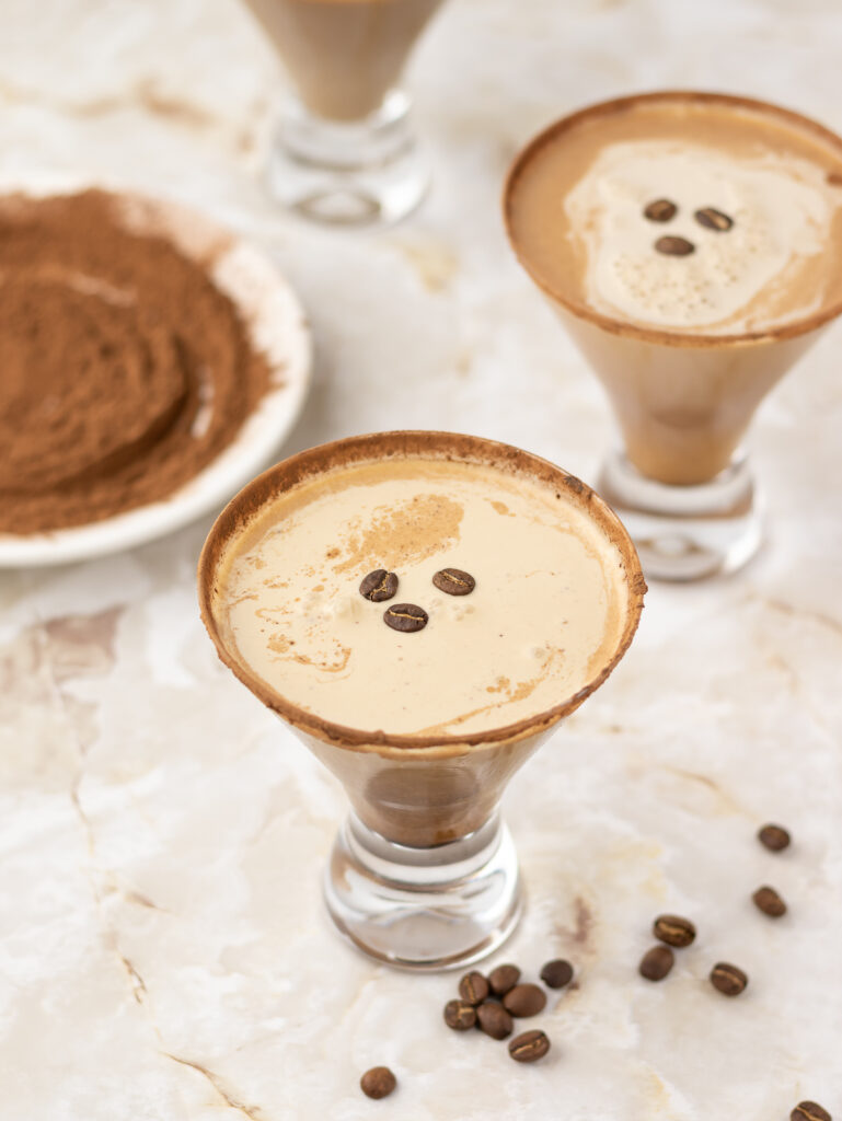 3 espresso martini mocktails with a cocoa rim and coffee bean garnish.