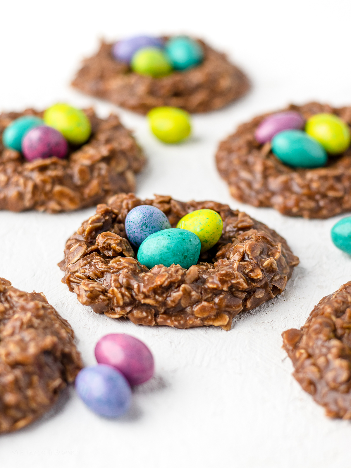 No bake cookies in the shape of birds nests with 3 candy eggs in the centers.
