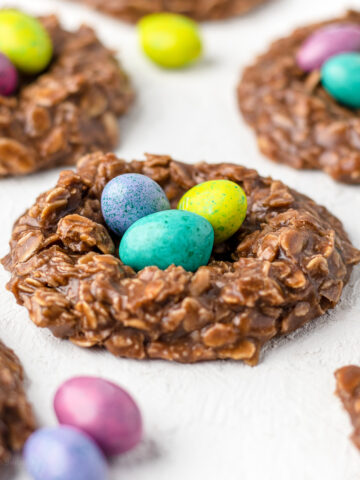 No bake birds nest cookies with candy eggs in them and more candy eggs around them.