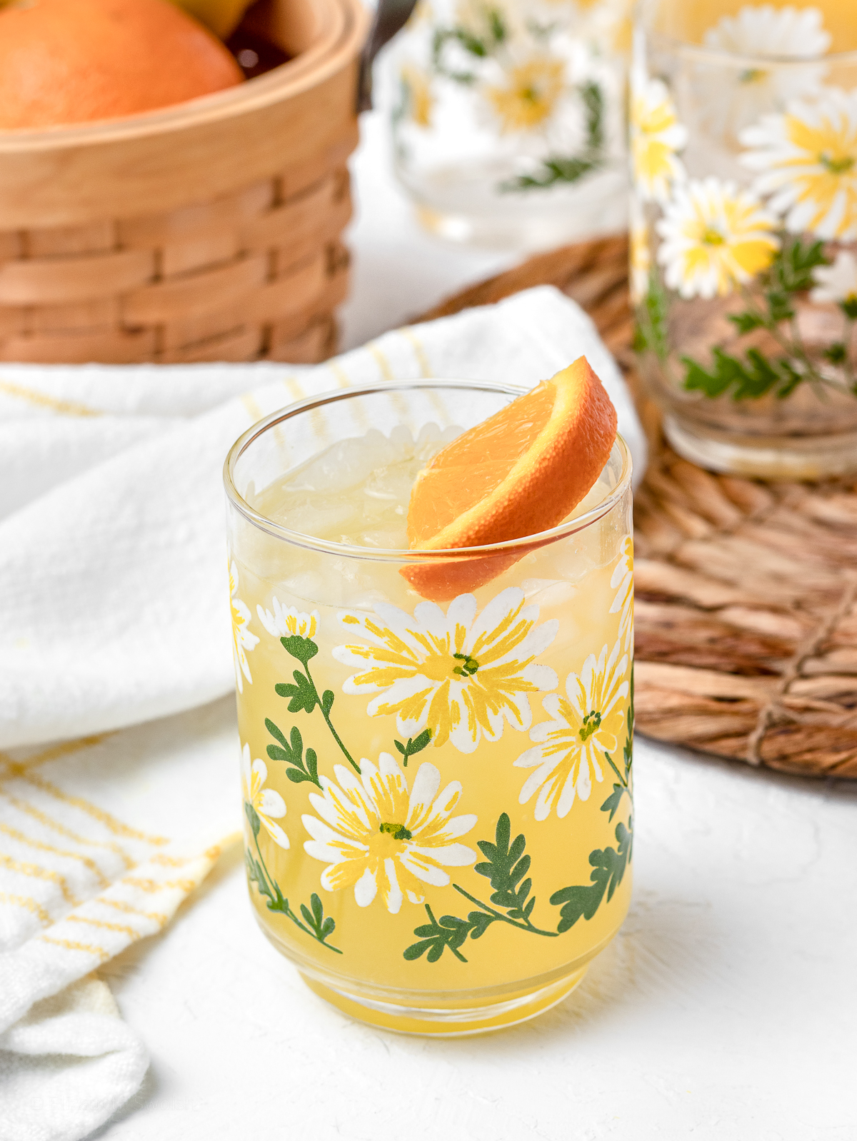 A glass of cold lemonade garnished with an orange wedge.