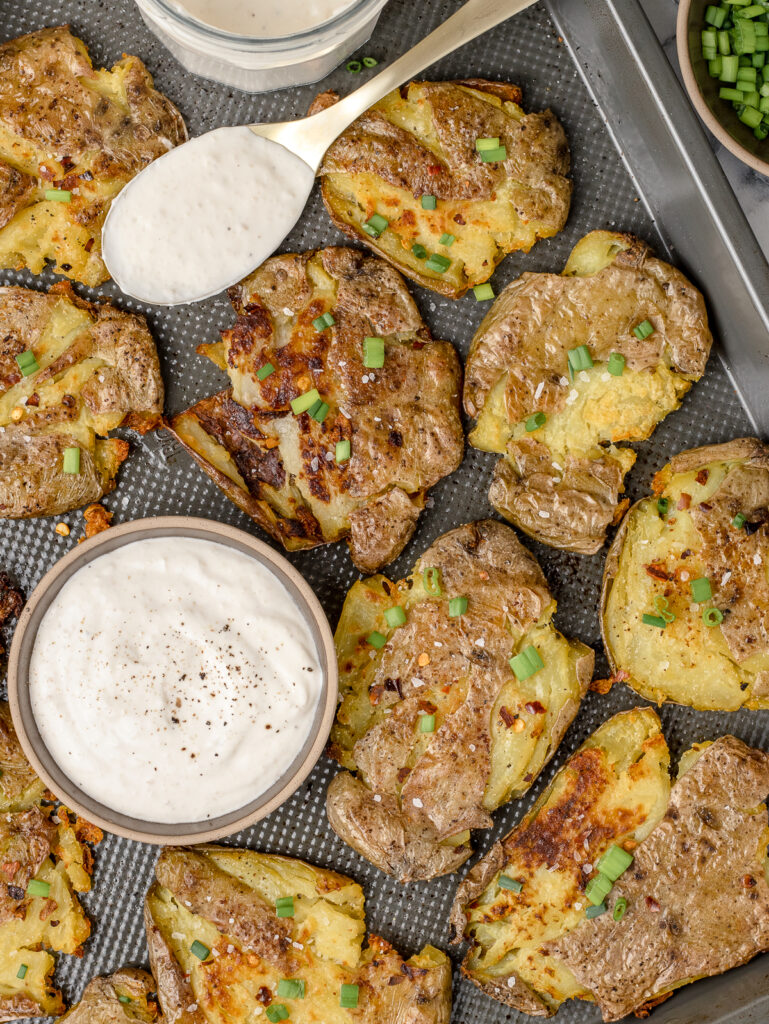 Smashed Potatoes topped with green onion and flaky sea salt with a side of creamy dipping sauce.
