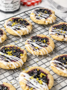 Cookies on a cooling rack topped with lemon glaze and lemon zest.