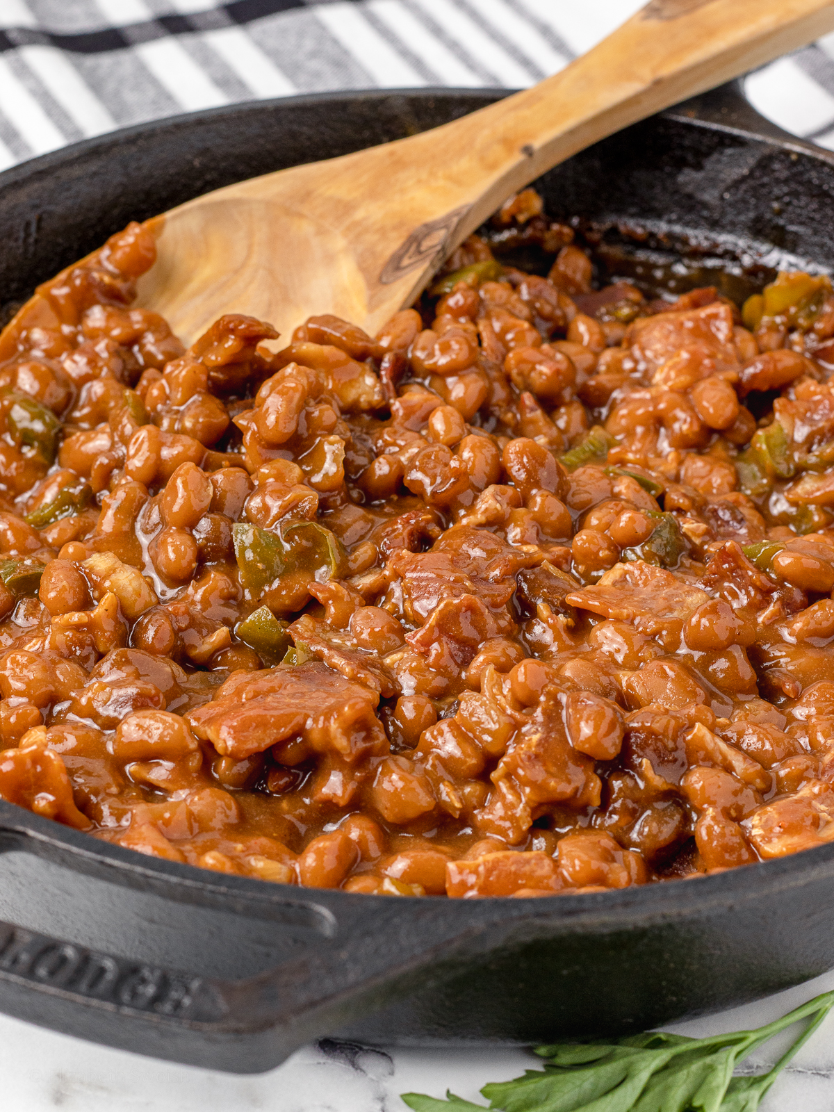 Smoked Baked Beans with a large spoon ready to serve.