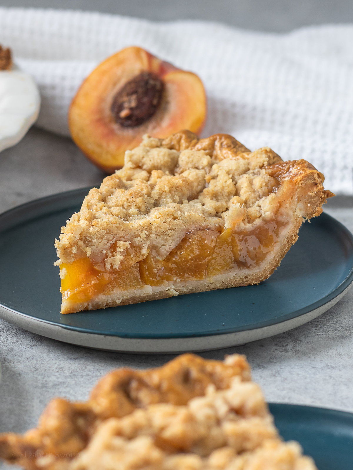 Two slices of pie with flaky crust, crumble topping, and a thick jammy peach mango filling.