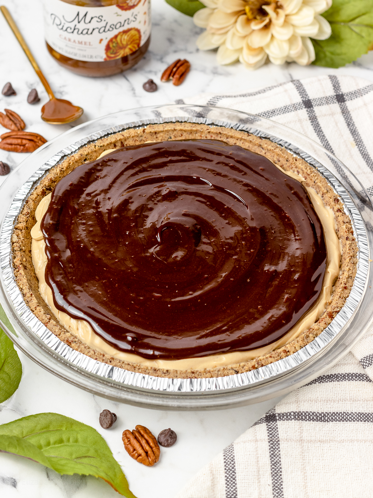 Smooth swirl of chocolate ganache on top of the pie. Pecan halves and caramel sauce on the side.