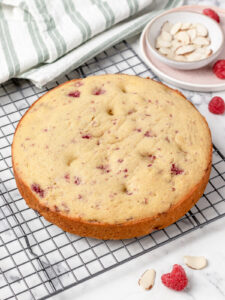 Baked raspberry and almond cake on a cooling rack cooling.