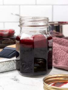 Jar of burgundy colored, sweet and spicy Blackberry BBQ Sauce.