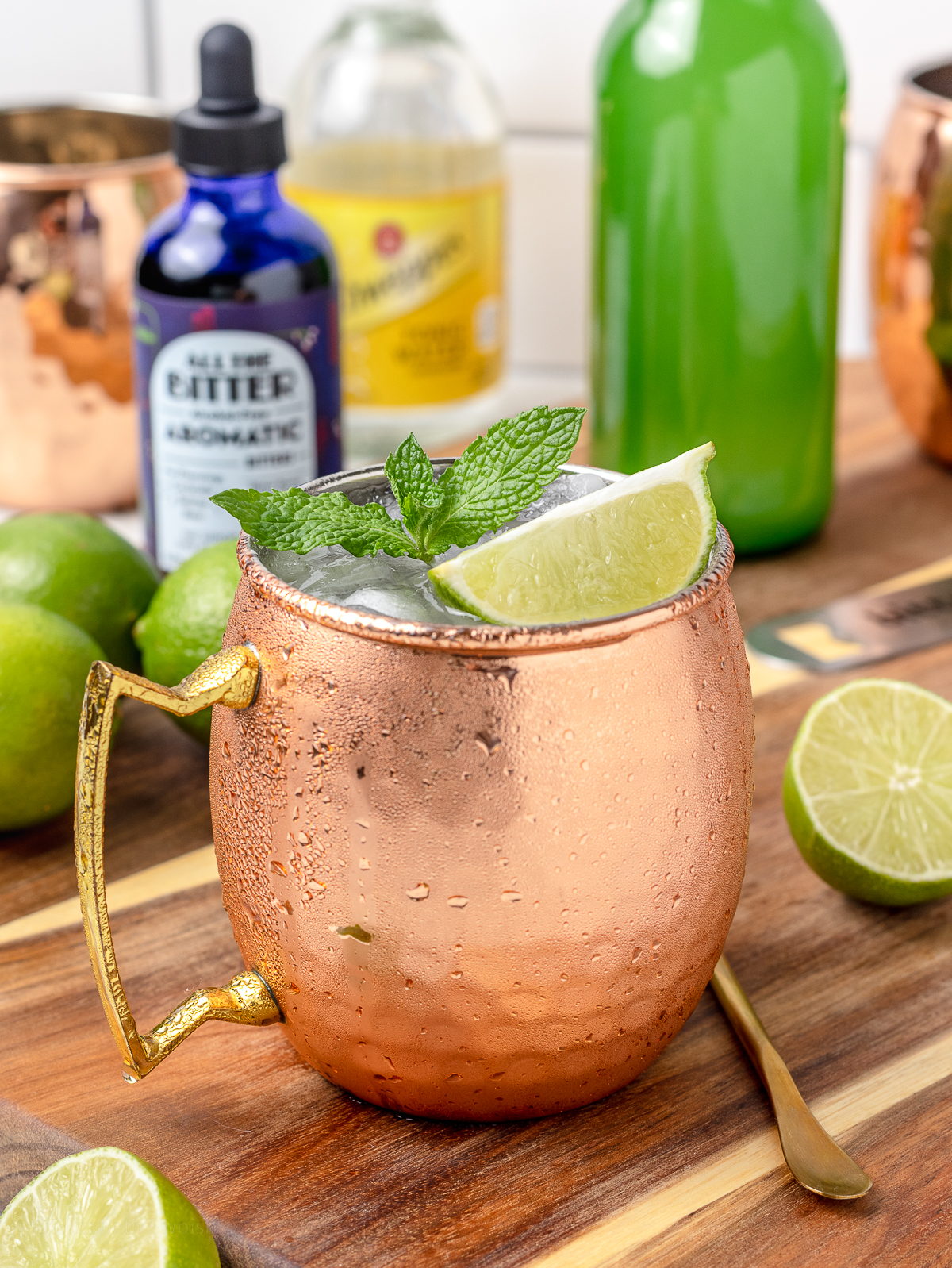 Moscow Mule Mocktail garnished with mint and lime wedge with ingredients in the background.