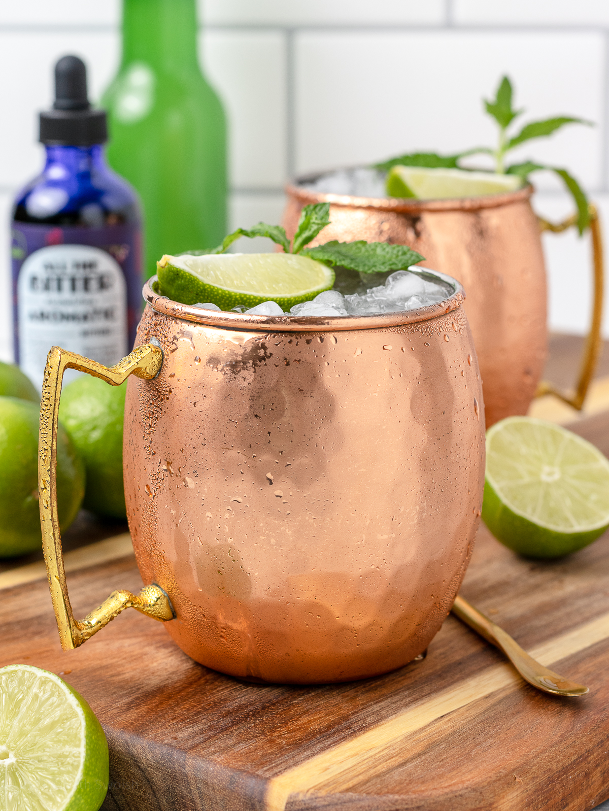 Moscow Mule Mocktails with aromatic bitters and a glass bottle of ginger beer in the background.