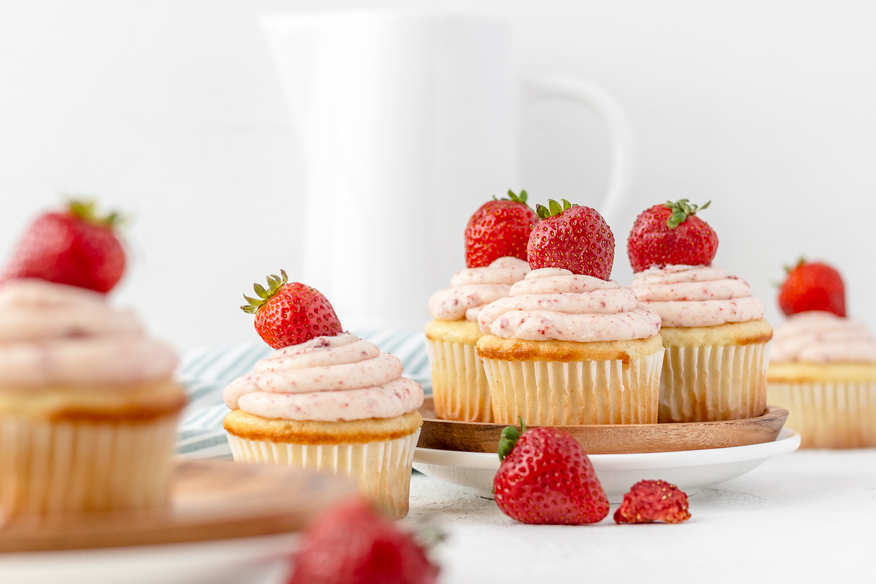 Strawberry Filled Cupcakes garnished with a fresh strawberry and set up on a table for eating.