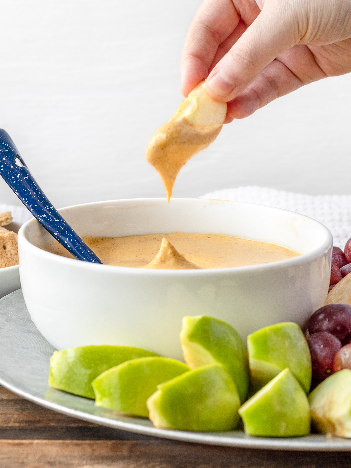 Fruit Dip flavored with pumpkin and maple being dipped with green apples.