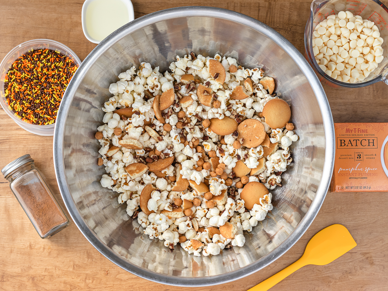 Big bowl of plain popcorn, pecans, caramel bits, and vanilla wafer cookies. Remaining ingredients for the coating on the side.
