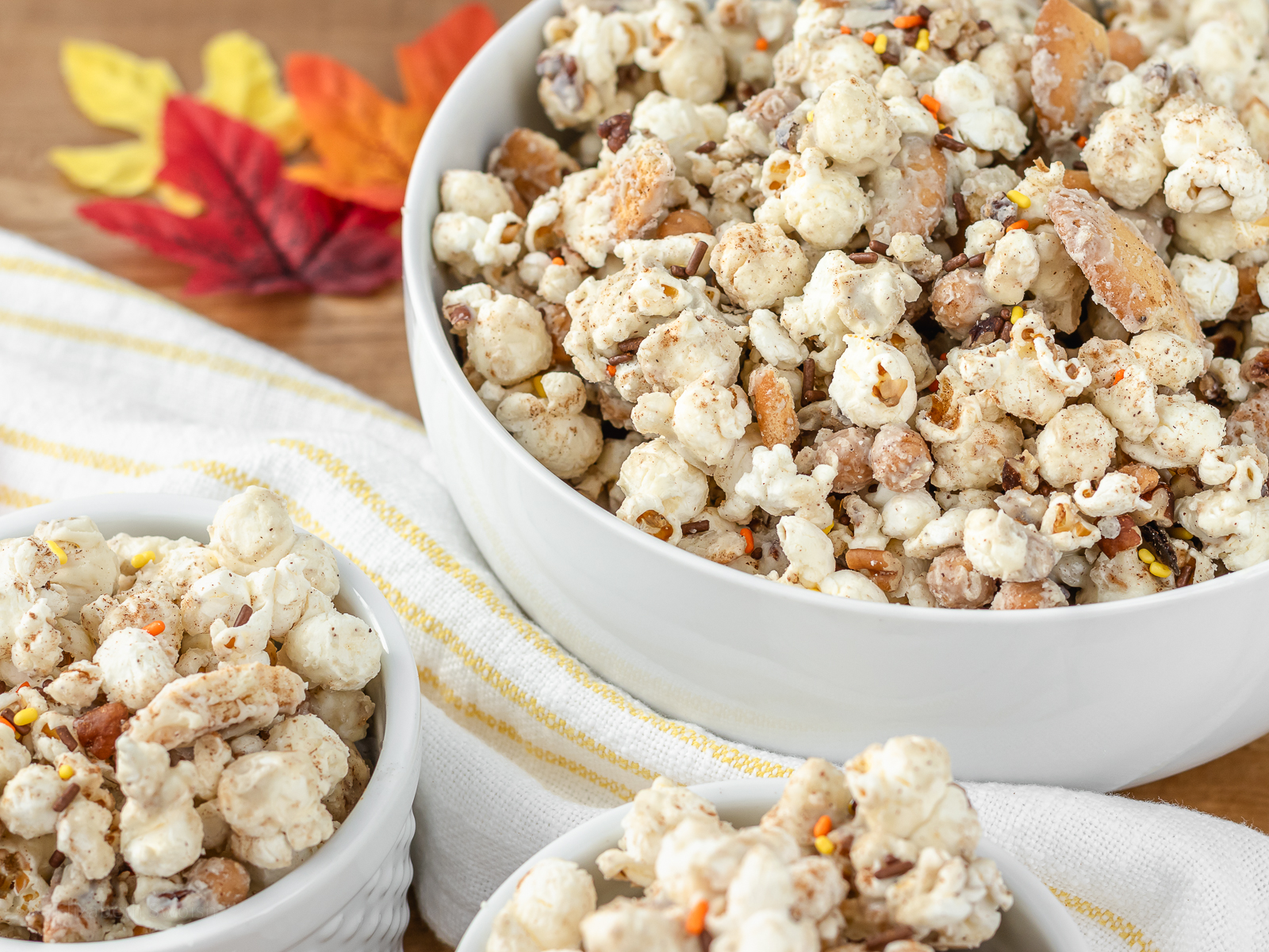 Close up of popcorn to see white chocolate pumpkin spice coated popcorn, caramel bits, and vanilla wafer cookies with sprinkles and pecans on top.