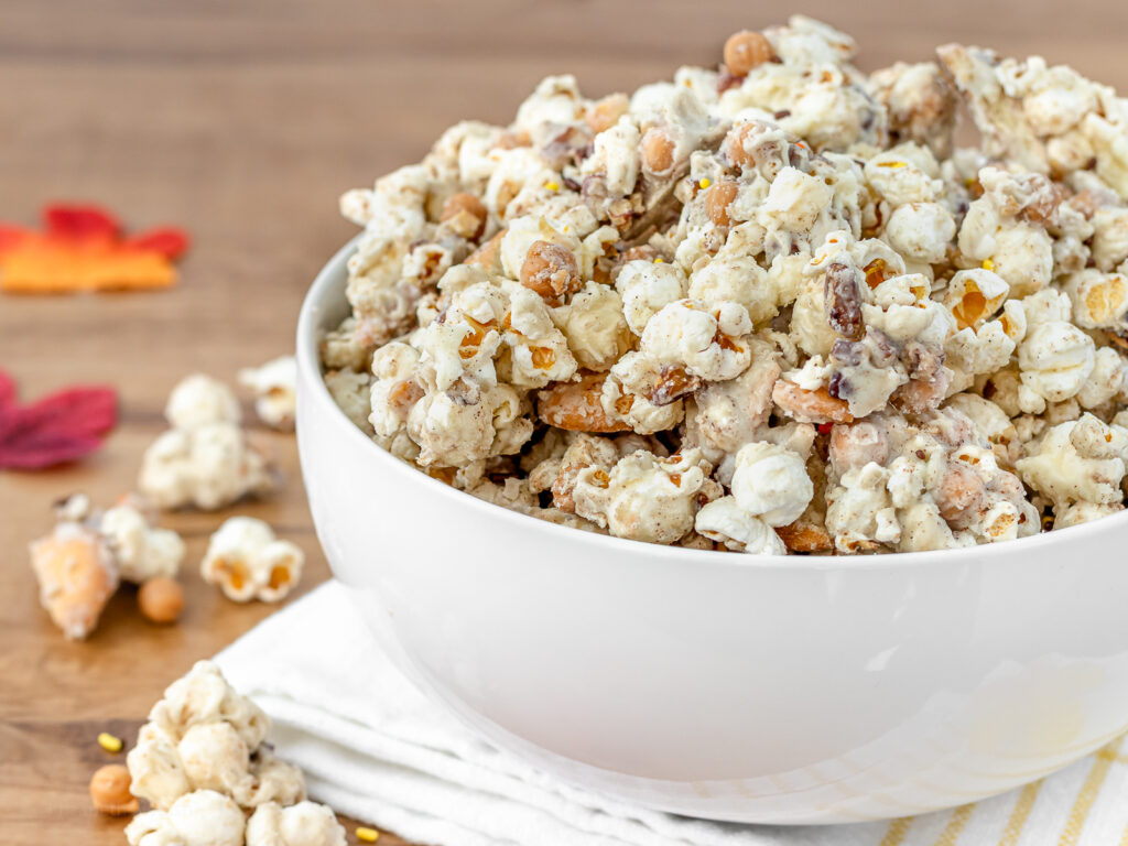 Close up of popcorn to see all the goodies coated in a white chocolate pumpkin spice coating.