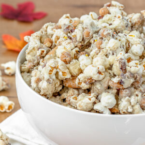 Close up of Fall Harvest Popcorn to see white chocolate pumpkin spice coated popcorn, caramel bits, and vanilla wafer cookies with sprinkles and pecans on top.