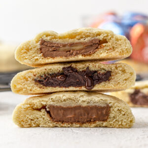 Stack of 3 chocolate filled cookies with a pile of candy in the background.