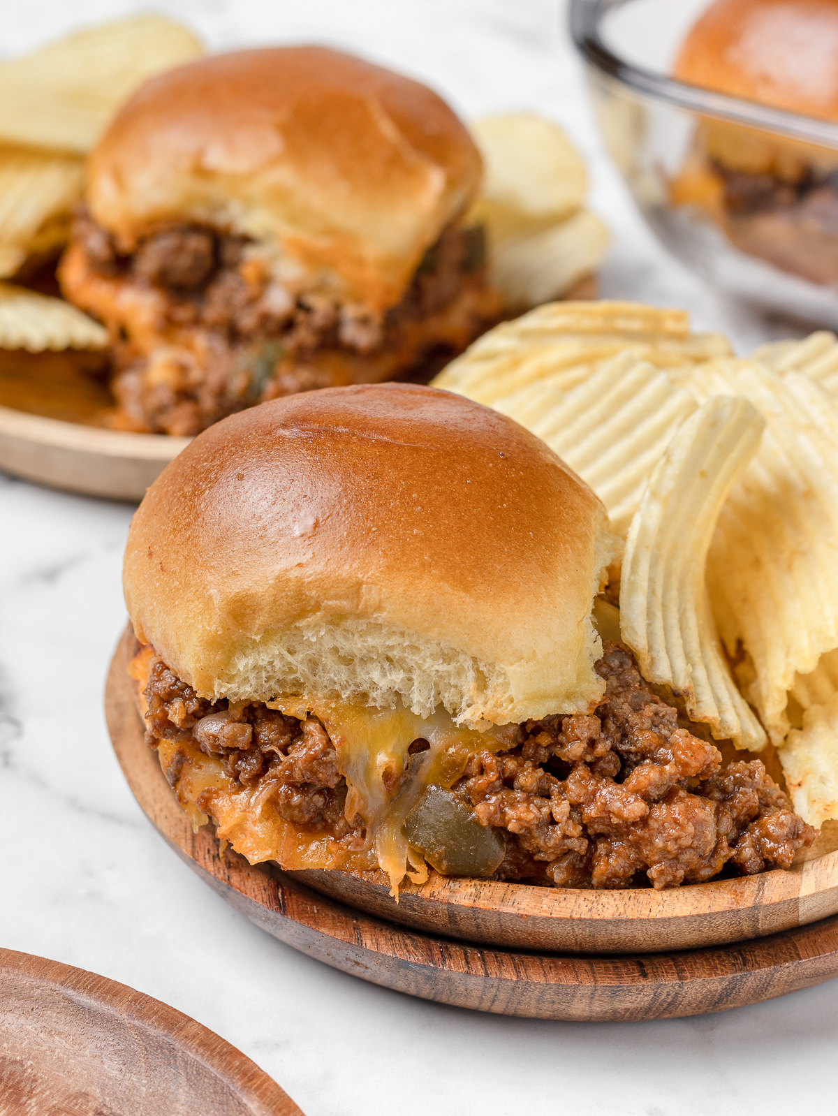 Two plates of sloppy joe sliders with chips.