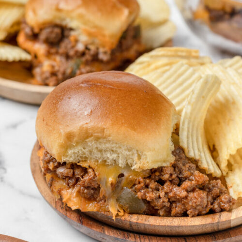 Two plates of sloppy joe sliders with chips.