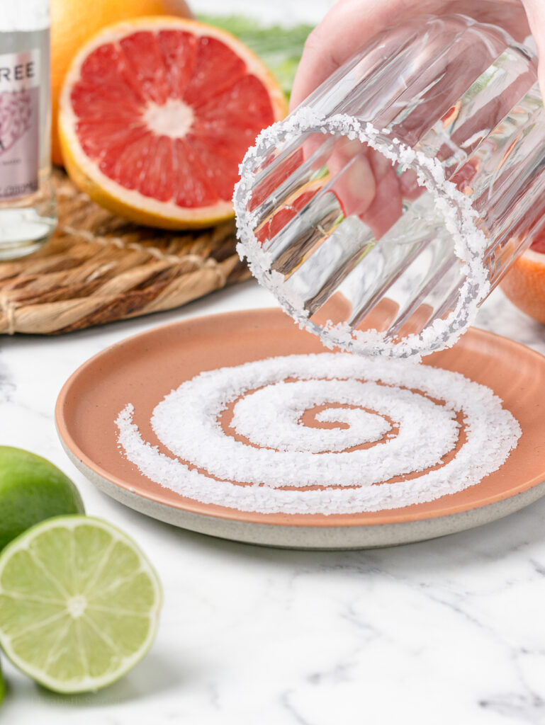 Step 1. Dipping the rim of a glass into lime juice and then salt.