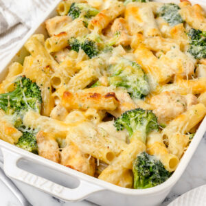 A large pan of hot and bubbly Baked Chicken and Broccoli Pasta topped with cheese. Ready to scoop onto plates to eat.