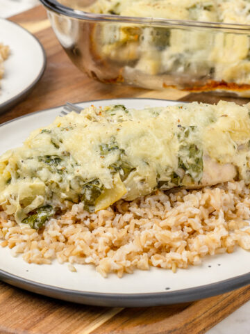 A plate of Spinach Artichoke Chicken Bake and rice, ready to cut and eat.