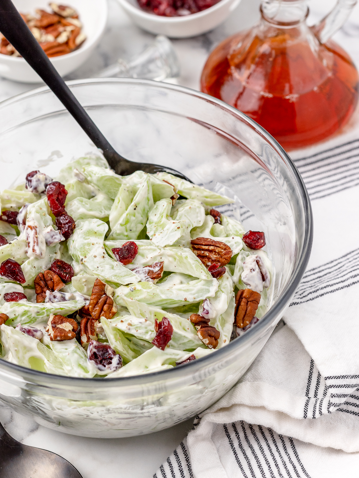 A big bowl salad and a spoon ready for serving. Creamy dressing coated celery, toasted pecans, and dried cranberries.