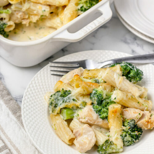 Baked Chicken and Broccoli Pasta on a plate and more in a large baking dish.